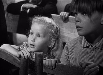 Movie still from “Forbidden Games” (1952), directed by René Clément – Two young children sitting on a bench in a church; Close Up shot, Low angle