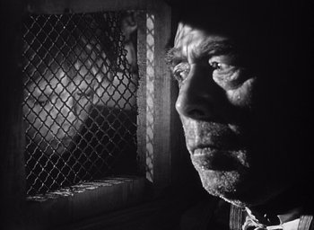 Movie still from “Forbidden Games” (1952), directed by René Clément – An old man looking out of a cage; Close Up shot, Low angle