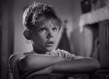 Movie still from “Forbidden Games” (1952), directed by René Clément – Black and white photograph of a young boy with his arms crossed; Close Up shot, High angle