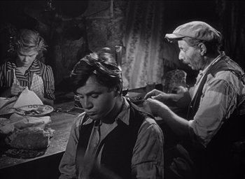 Movie still from “Forbidden Games” (1952), directed by René Clément – An old photo of a man getting his hair cut; Medium shot, Over the shoulder angle