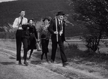 Movie still from “Forbidden Games” (1952), directed by René Clément – An old black and white photo of a group of people walking down a dirt road; Wide shot, Low angle