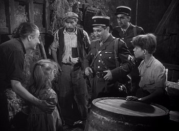 Movie still from “Forbidden Games” (1952), directed by René Clément – A group of people standing next to each other in a room; Medium shot, Over the shoulder angle