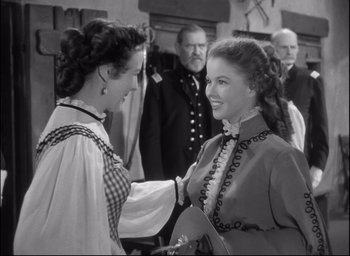 Movie still from “Fort Apache” (1948), directed by John Ford – Two women are greeting each other in an old photo; Medium shot, Over the shoulder angle