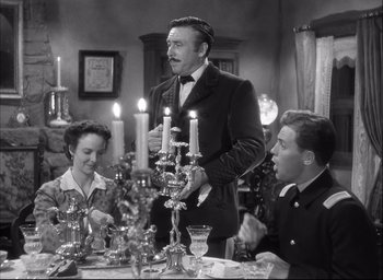Movie still from “Fort Apache” (1948), directed by John Ford – A man standing at a dinner table with two women; Medium shot, High angle