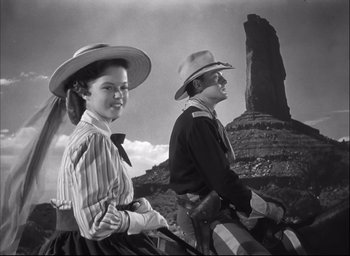 Movie still from “Fort Apache” (1948), directed by John Ford – A man and a woman are standing in front of a rock formation; Medium shot, Low angle