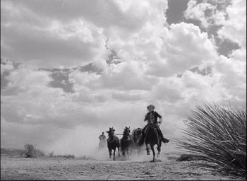 Movie still from “Fort Apache” (1948), directed by John Ford – A man on a horse is leading a group of horses; Extreme Wide shot, Low angle