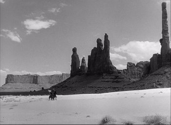 Movie still from “Fort Apache” (1948), directed by John Ford – A man riding a horse through the desert; Extreme Wide shot, Low angle