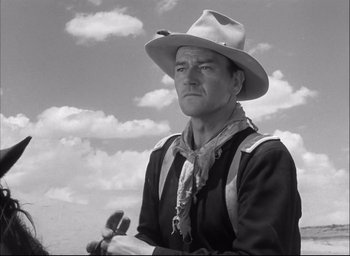 Movie still from “Fort Apache” (1948), directed by John Ford – A man wearing a cowboy hat while holding a gun; Medium shot, Low angle