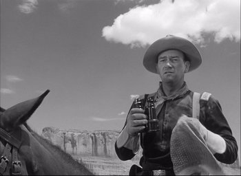 Movie still from “Fort Apache” (1948), directed by John Ford – A man in a cowboy hat holding a beer; Medium shot, Low angle