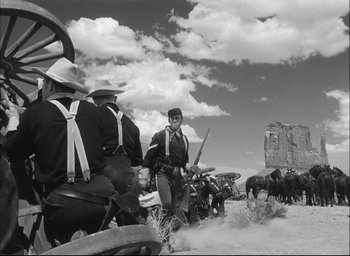 Movie still from “Fort Apache” (1948), directed by John Ford – A group of men riding horses on a dirt road; Wide shot, Low angle