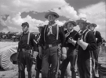 Movie still from “Fort Apache” (1948), directed by John Ford – A black and white photo of a group of men standing next to each other; Medium shot, Low angle