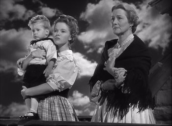 Movie still from “Fort Apache” (1948), directed by John Ford – Two women and a boy standing next to each other in front of a cloudy sky; Medium shot, Low angle