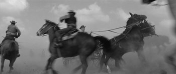 Movie still from “Forty Guns” (1957), directed by Samuel Fuller – A black - and - white photo of horses pulling a carriage; Wide shot, Low angle