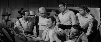 Movie still from “Forty Guns” (1957), directed by Samuel Fuller – A group of men standing next to each other in a room; Medium shot, Over the shoulder angle