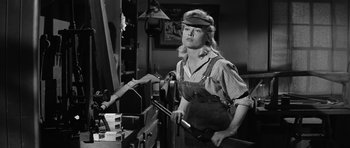 Movie still from “Forty Guns” (1957), directed by Samuel Fuller – A black and white photo of a woman holding a pair of tools; Medium shot, Low angle