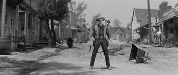 Movie still from “Forty Guns” (1957), directed by Samuel Fuller – A man in a cowboy hat holding two guns; Wide shot, Low angle