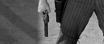 Movie still from “Forty Guns” (1957), directed by Samuel Fuller – A man holding a gun with a holster in his hand; Extreme Close Up shot, Low angle