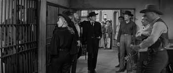 Movie still from “Forty Guns” (1957), directed by Samuel Fuller – A black and white photo of a group of men in suits and hats; Medium shot, Over the shoulder angle