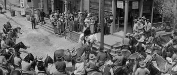 Movie still from “Forty Guns” (1957), directed by Samuel Fuller – A group of people sitting on the side of a building; Wide shot, High angle