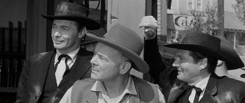 Movie still from “Forty Guns” (1957), directed by Samuel Fuller – A group of men wearing hats in a black - and - white photo; Medium shot, Over the shoulder angle