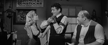 Movie still from “Forty Guns” (1957), directed by Samuel Fuller – A man holding a teddy bear in his hands while standing next to a woman; Medium shot, Over the shoulder angle