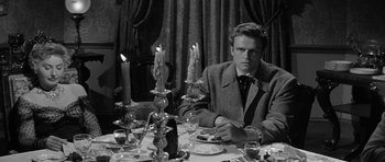 Movie still from “Forty Guns” (1957), directed by Samuel Fuller – A black and white photo of a man sitting at a dinner table; Medium shot, Over the shoulder angle