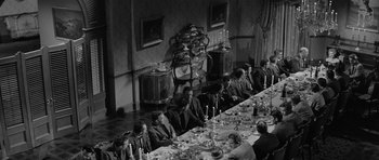 Movie still from “Forty Guns” (1957), directed by Samuel Fuller – A group of people sitting around a long table; Wide shot, High angle