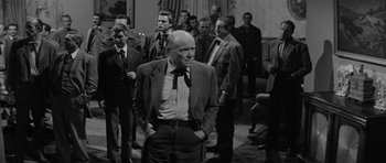 Movie still from “Forty Guns” (1957), directed by Samuel Fuller – An old photo of a group of men in suits; Medium shot, Over the shoulder angle