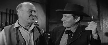 Movie still from “Forty Guns” (1957), directed by Samuel Fuller – A man in a black hat and a man in a black suit; Close Up shot, Over the shoulder angle