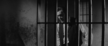 Movie still from “Forty Guns” (1957), directed by Samuel Fuller – A black and white photo of a man behind bars; Medium shot, Low angle