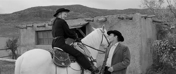 Movie still from “Forty Guns” (1957), directed by Samuel Fuller – A man and a woman sitting on a white horse; Medium shot, Over the shoulder angle