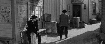 Movie still from “Forty Guns” (1957), directed by Samuel Fuller – A man in a suit and a man in a hat; Wide shot, Over the shoulder angle