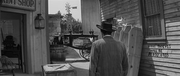 Movie still from “Forty Guns” (1957), directed by Samuel Fuller – A black and white photo of a man looking at a horse drawn carriage; Wide shot, Over the shoulder angle