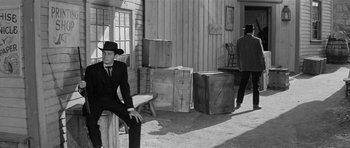 Movie still from “Forty Guns” (1957), directed by Samuel Fuller – A black and white photo of a man sitting on a bench; Wide shot, Over the shoulder angle