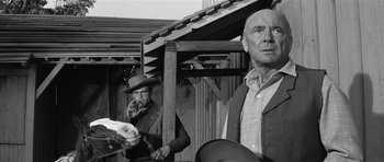 Movie still from “Forty Guns” (1957), directed by Samuel Fuller – Two men standing next to each other in front of a building; Medium shot, Low angle