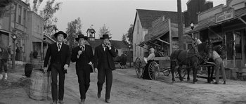 Movie still from “Forty Guns” (1957), directed by Samuel Fuller – A couple of men walking down a dirt road next to a horse drawn carriage; Wide shot, Low angle