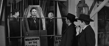 Movie still from “Forty Guns” (1957), directed by Samuel Fuller – A black and white photo of a man looking through a window; Medium shot, Over the shoulder angle