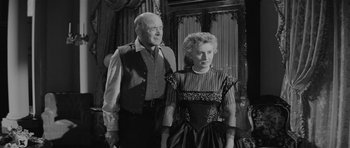 Movie still from “Forty Guns” (1957), directed by Samuel Fuller – An older man standing next to an older woman; Medium shot, Over the shoulder angle