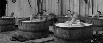 Movie still from “Forty Guns” (1957), directed by Samuel Fuller – A group of men sitting in wooden tubs in a room; Medium shot, High angle