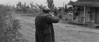 Movie still from “Forty Guns” (1957), directed by Samuel Fuller – A man is taking a picture with a camera; Medium shot, Over the shoulder angle