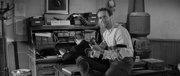 Movie still from “Forty Guns” (1957), directed by Samuel Fuller – A man sitting on the ground with a book in his hand; Medium shot, Low angle