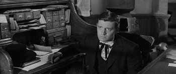 Movie still from “Forty Guns” (1957), directed by Samuel Fuller – A black and white photo of a man sitting at a desk; Close Up shot, Over the shoulder angle