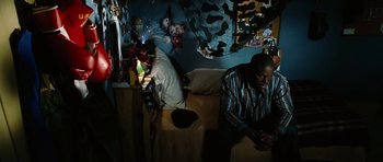 Movie still from “Four Brothers” (2005), directed by John Singleton – A man sitting on top of a bed next to another man; Medium shot, High angle