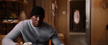 Movie still from “Four Brothers” (2005), directed by John Singleton – A man in a black hat is sitting in a living room; Close Up shot, Over the shoulder angle