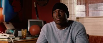 Movie still from “Four Brothers” (2005), directed by John Singleton – A man sitting in front of a tv in front of a basketball; Close Up shot, High angle