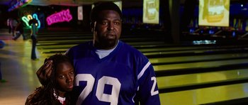 Movie still from “Four Brothers” (2005), directed by John Singleton – A man in a football jersey standing next to a bench; Close Up shot, Low angle