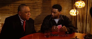 Movie still from “Four Brothers” (2005), directed by John Singleton – Two men sitting at a wooden table with cards in front of them; Medium shot, Over the shoulder angle