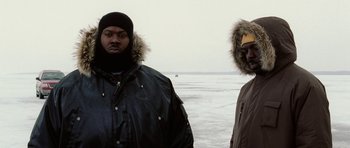 Movie still from “Four Brothers” (2005), directed by John Singleton – Two men standing next to each other on the beach; Medium shot, Low angle
