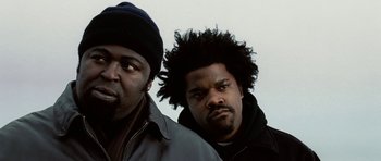 Movie still from “Four Brothers” (2005), directed by John Singleton – Two men standing next to each other in front of a sky background; Close Up shot, Low angle
