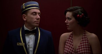 Movie still from “Four Rooms” (1995), directed by Robert Rodriguez – A man and a woman standing next to each other in front of a red wall; Medium shot, Low angle